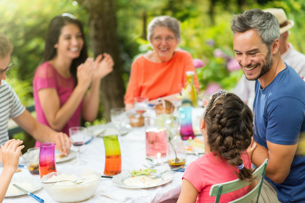 Multi-generation family having lunch in the garden in summer. Dad kidding with his daughter. Focus on the little girl